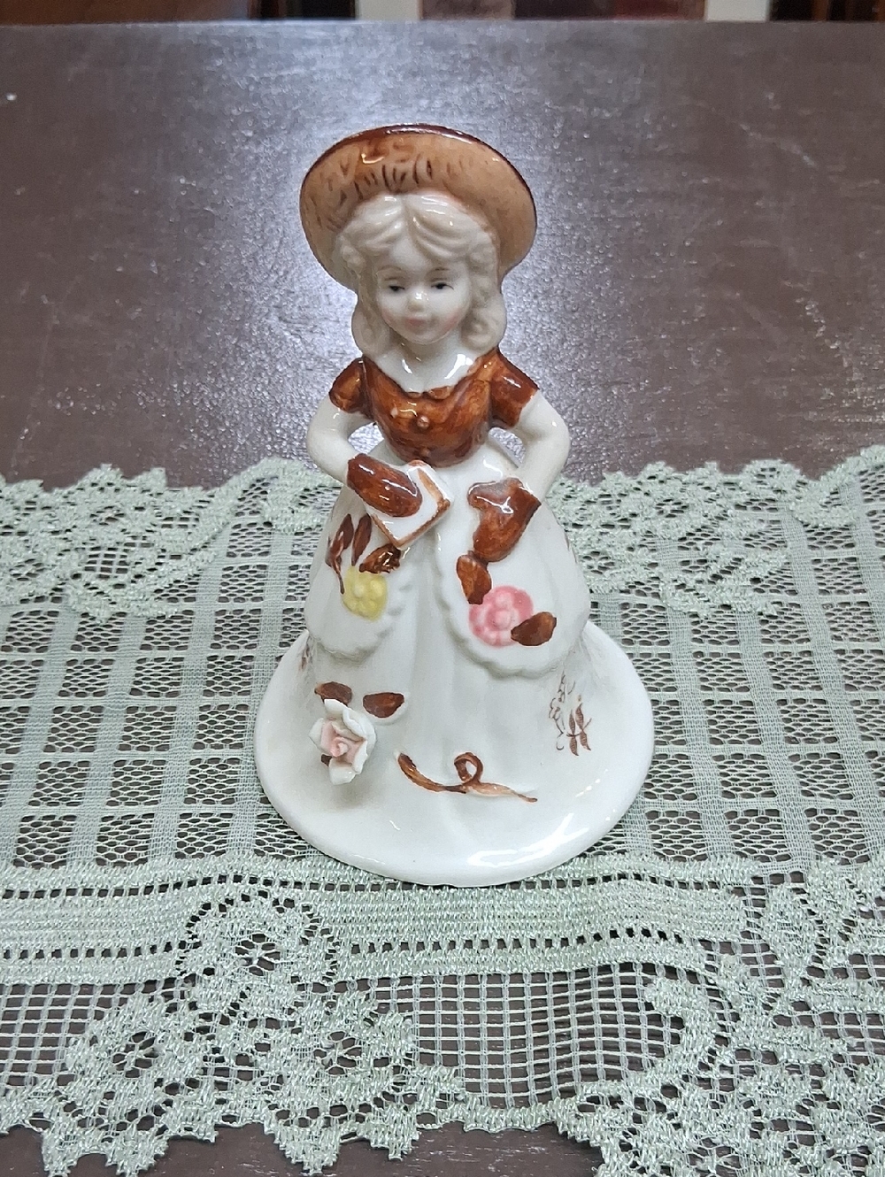 Vintage Woolbro porcelain figurine bell featuring a girl in a brown dress.